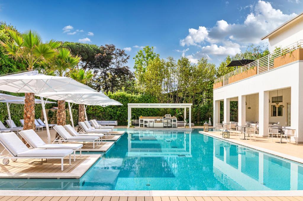 马尔米堡Resort Miramonti的房屋旁的游泳池配有椅子和遮阳伞