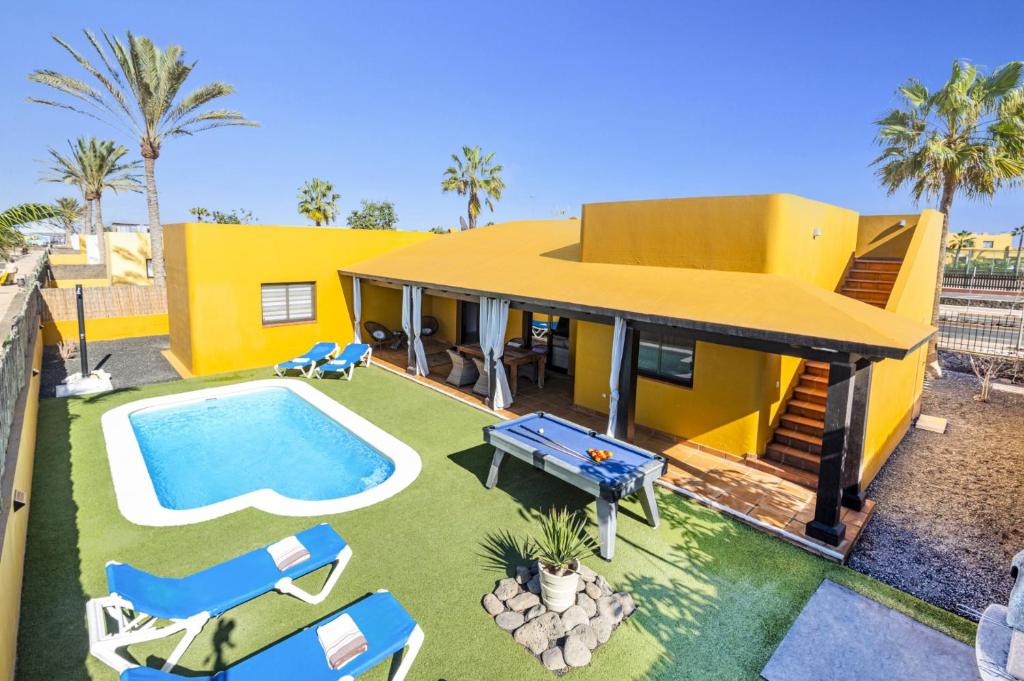 科拉雷侯Villa Papagayo Deluxe by Villa Plus的黄色的房子,设有游泳池和一些椅子