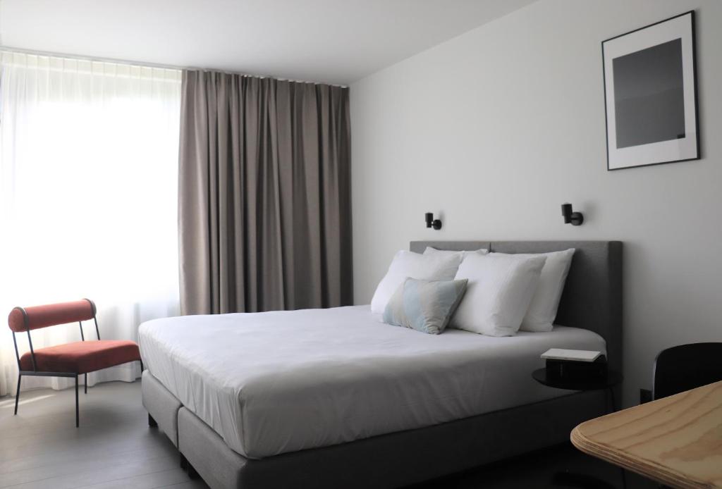 安特卫普Hotel National Antwerp的配有一张床和一把椅子的酒店客房