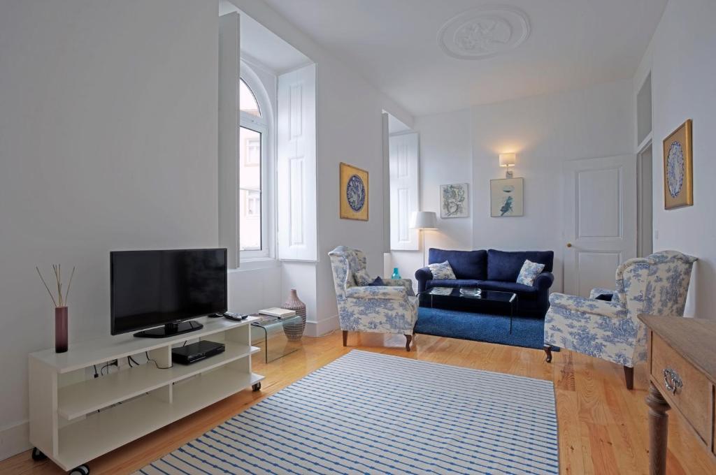里斯本Portas do Castelo Apartments的客厅配有电视和蓝色沙发。