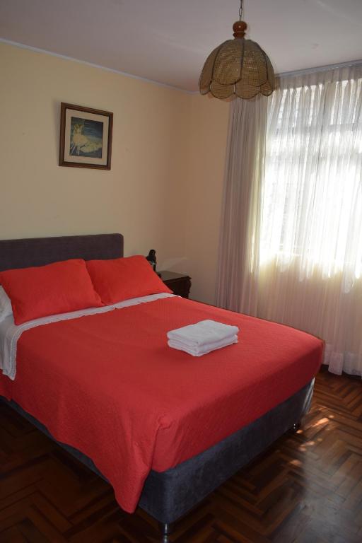 特鲁希略Hostal Donde Alberto的一间卧室配有一张带红色床单的床和一扇窗户。