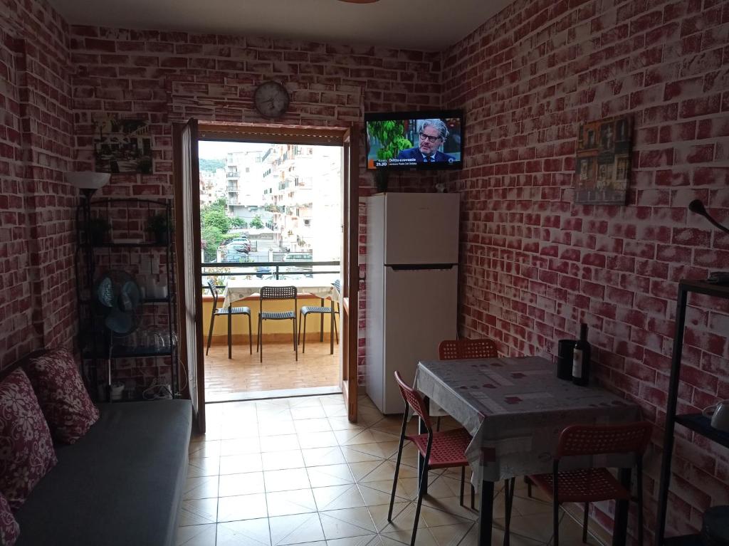斯卡莱阿Appartamento Via Pitagora的厨房配有桌子,砖墙上配有电视