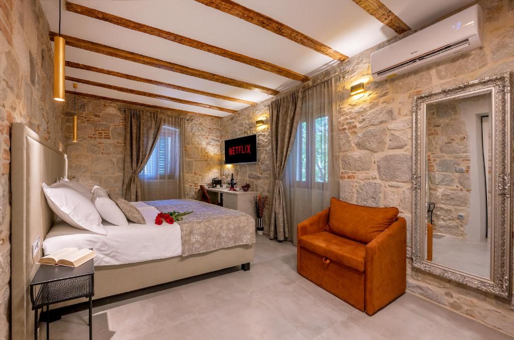 斯普利特Old Spalatrum Luxury Rooms的一间卧室配有一张床和一把椅子