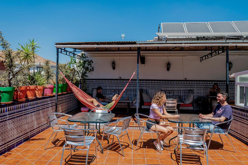 塞维利亚Hostel Triana Backpackers的一群人坐在桌子上,屋顶上设有吊床