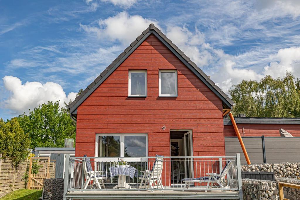 哈里斯莱fewo1846 - Palstek - elegante Maisonettewohnung auf parkähnlichem Grundstück的红色的房子,甲板上配有桌椅