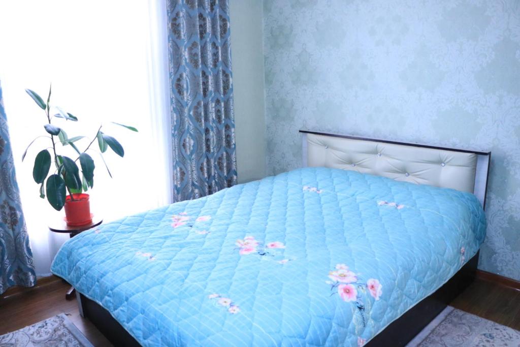 Ysyk-KölGuest House Oimo的一张带蓝色棉被的床,上面有粉红色的花朵