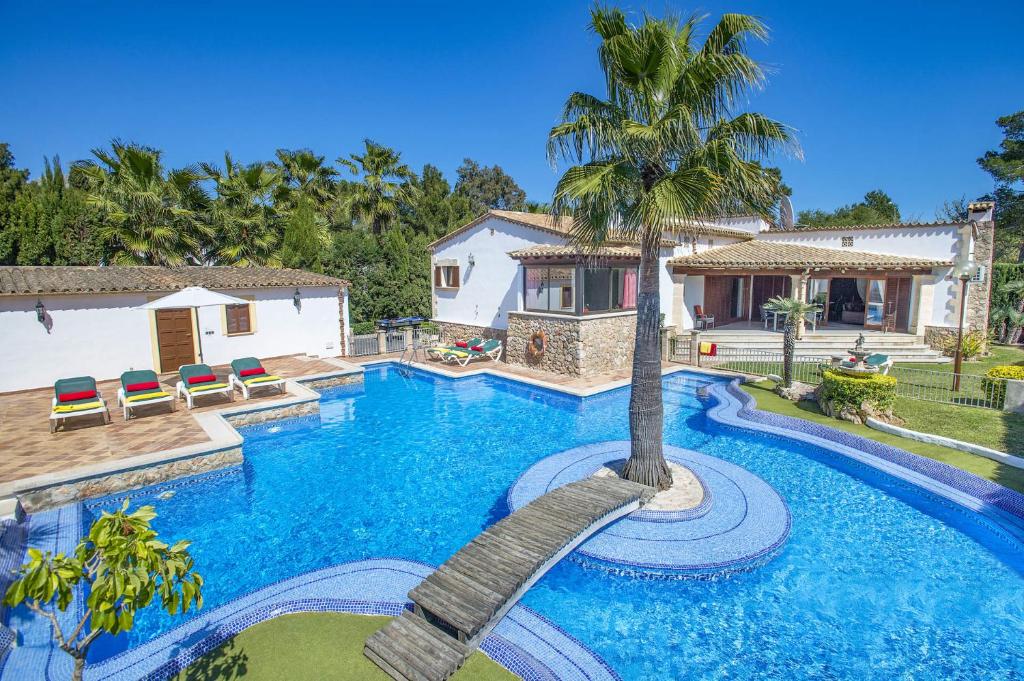 埃尔波特Villa Pinos by Villa Plus的一座房子旁的游泳池,里面种着棕榈树