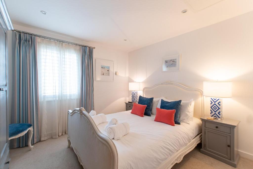 卡比斯贝Wingtips的一间卧室配有白色的床和蓝色和红色枕头