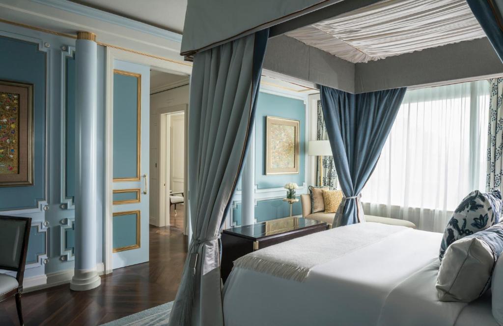 雅加达雅加达四季酒店的一间拥有蓝色墙壁的卧室、一张床和窗户