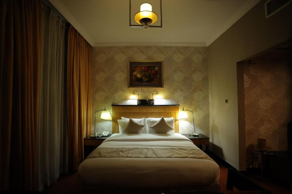 沙迦CREEK GATE HOTEL-BAITHANS的酒店客房,配有一张带两盏灯的床