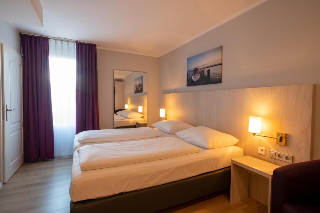 不来梅港Nautic Hotel Bremerhaven的酒店客房设有两张床和窗户。