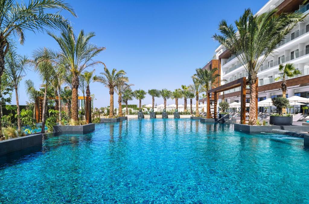阿依纳帕Amanti, MadeForTwo Hotels - Ayia Napa的一座楼前棕榈树游泳池