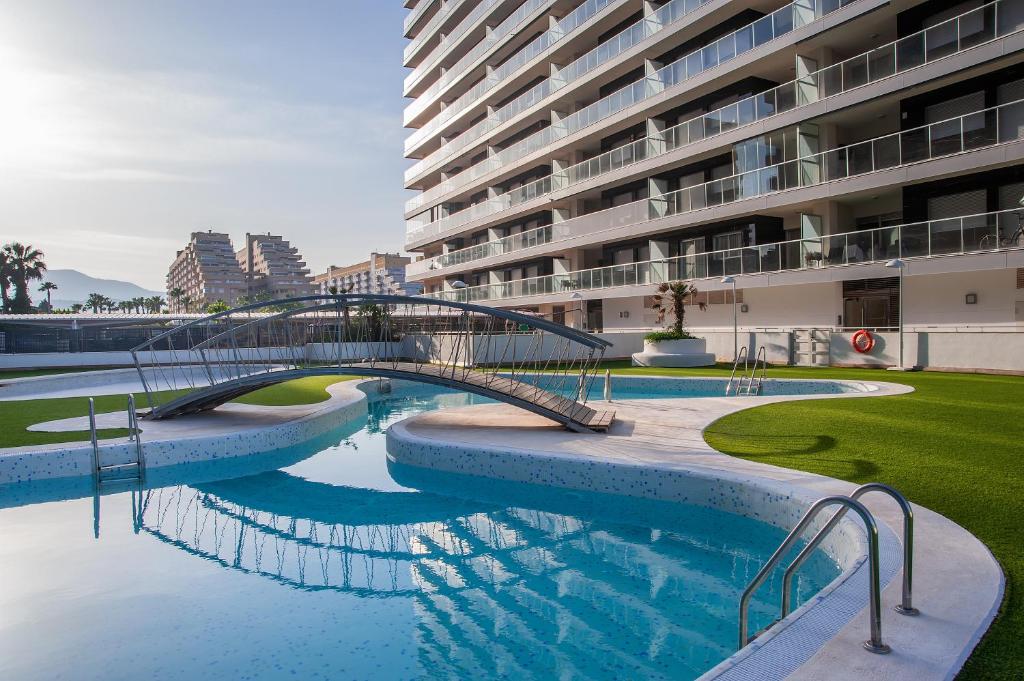 奥罗佩萨德尔马Holiday Deluxe Apartment Miramar Marina d'or的一座建筑物中一座游泳池上的桥梁