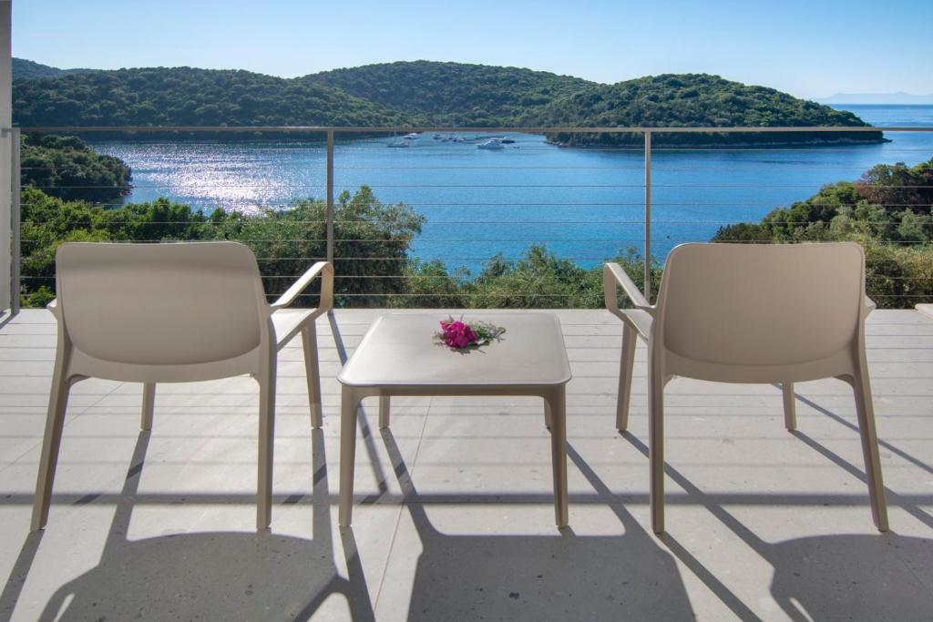塞沃塔Sivota Deamaris Luxury Boutique Hotel的阳台上配有两把椅子和一张带花卉的桌子