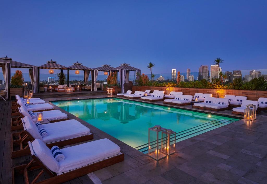 洛杉矶60比佛利山酒店的一个带躺椅的游泳池和一间酒店