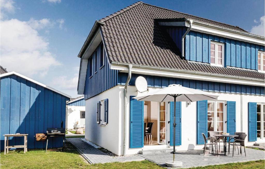 阿尔特费尔Ferienhaus 5 Altefhr的蓝色和白色的房子,配有桌子和雨伞