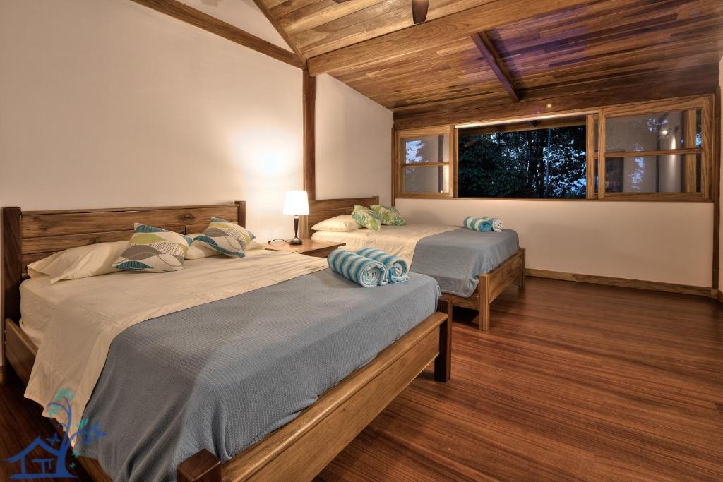 蓬塔乌巴Luxury Villa Panorama Verde Pool House的客房内设有两张床,铺有木地板,设有窗户。