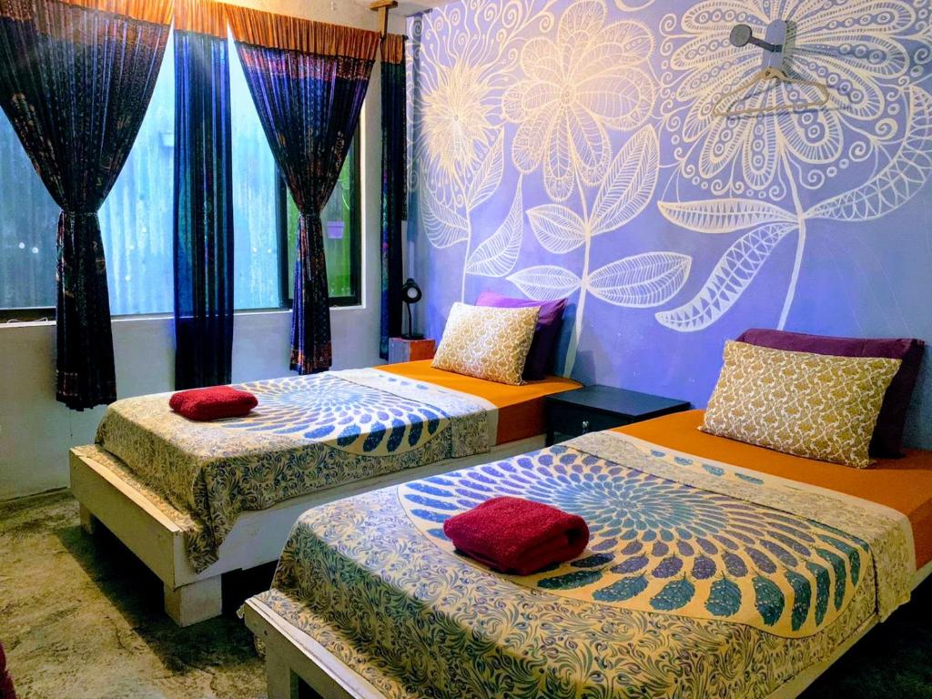 雅科Casajungla Hostel的一间卧室设有两张床和一堵带花卉壁画的墙壁