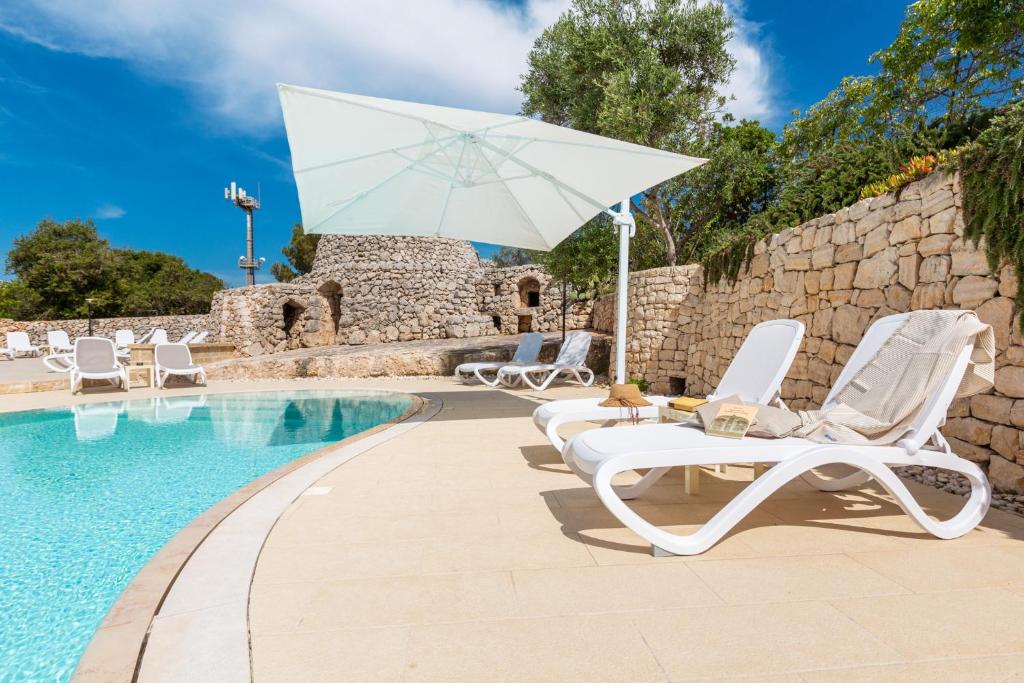 托雷瓦多米拉马尔公寓式酒店的一组椅子和一把遮阳伞,位于游泳池旁