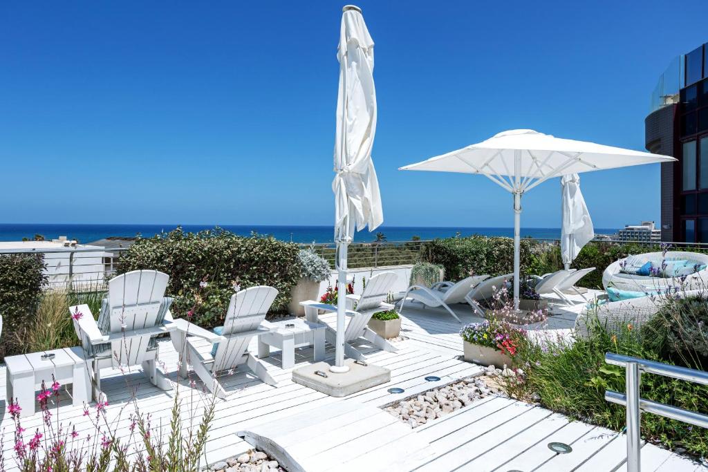 特拉维夫沙洛姆酒店 - 阿特拉斯精品酒店的一个带白色椅子和遮阳伞的庭院和大海