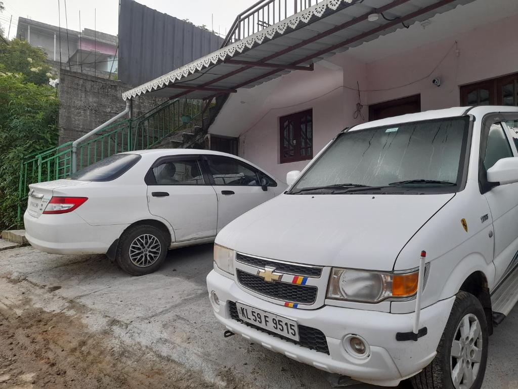 蒙纳Munnar Brindavan Cottage的两辆白色汽车停在大楼前