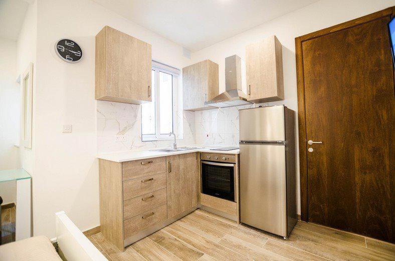 瓦莱塔Valletta Republic Suite的厨房配有不锈钢冰箱和木制橱柜