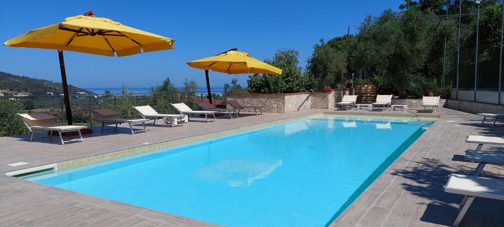 佩斯基奇Liberato Puglia Vacanze的一个带两把遮阳伞和椅子的游泳池