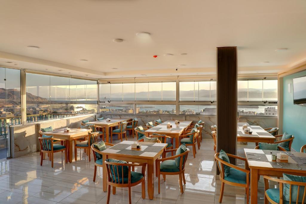亚喀巴Turquoise Hotel的餐厅设有木桌、椅子和窗户。