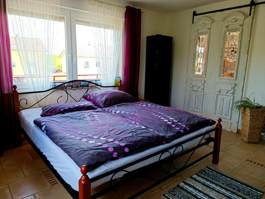 BrackenheimCasa del Norte的一间卧室配有一张带紫色床单的床和窗户。