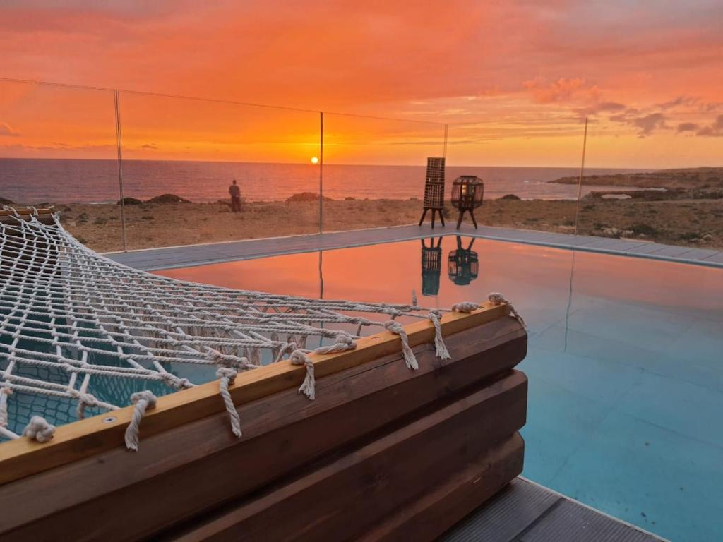 卡尔帕索斯Tramonto Luxury Villa No2 - Breathtaking sunset view的日落时分享有海洋美景的无边泳池