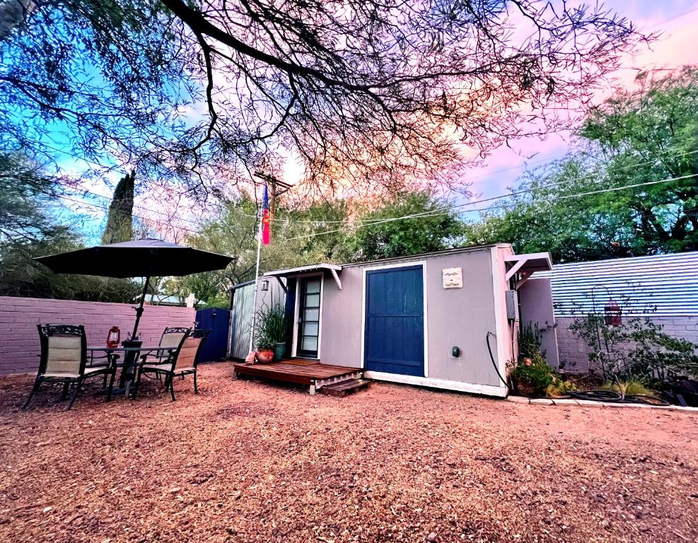 土桑Peaceful Tucson Tiny House Getaway with Backyard的一个带桌椅和雨伞的小棚子