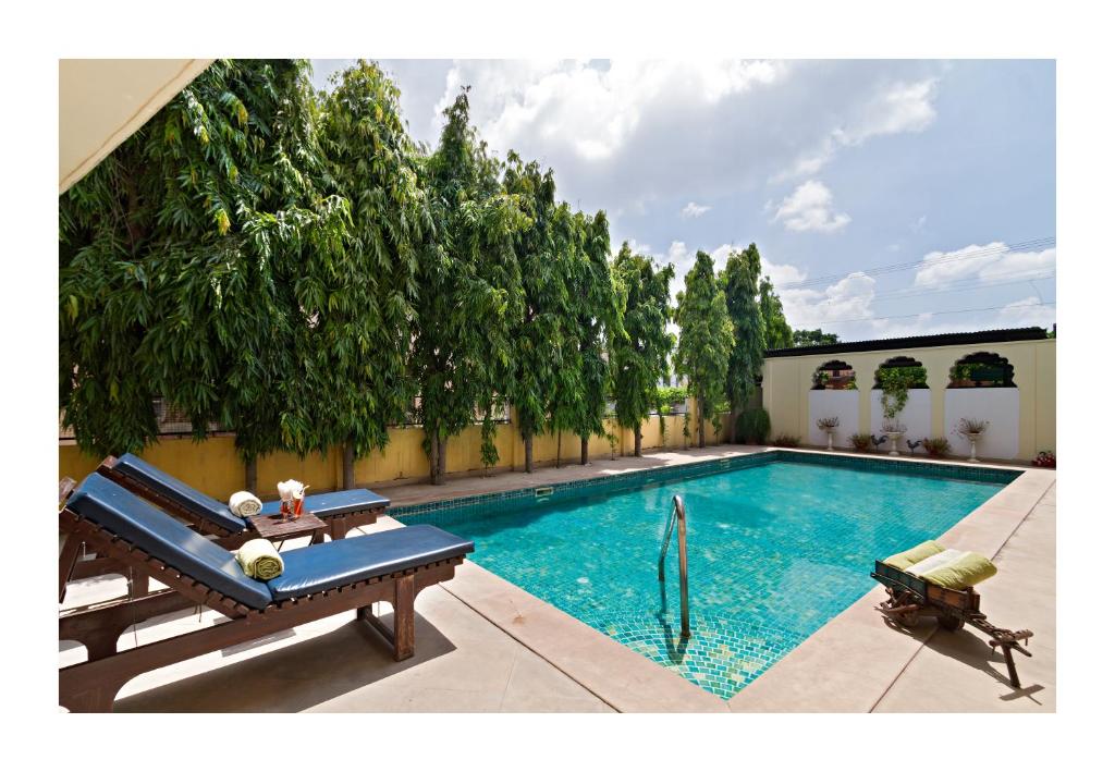 斋浦尔Dera Rawatsar - Heritage Hotel的一座游泳池,旁边设有2个长椅