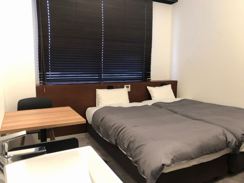天草市阳光之路酒店的一间卧室设有两张床、一张桌子和一个窗口