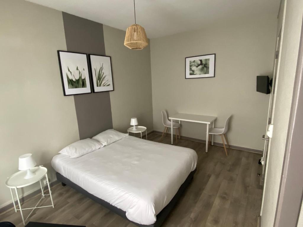 多勒Le Relais de la Gare的卧室配有白色的床和桌子