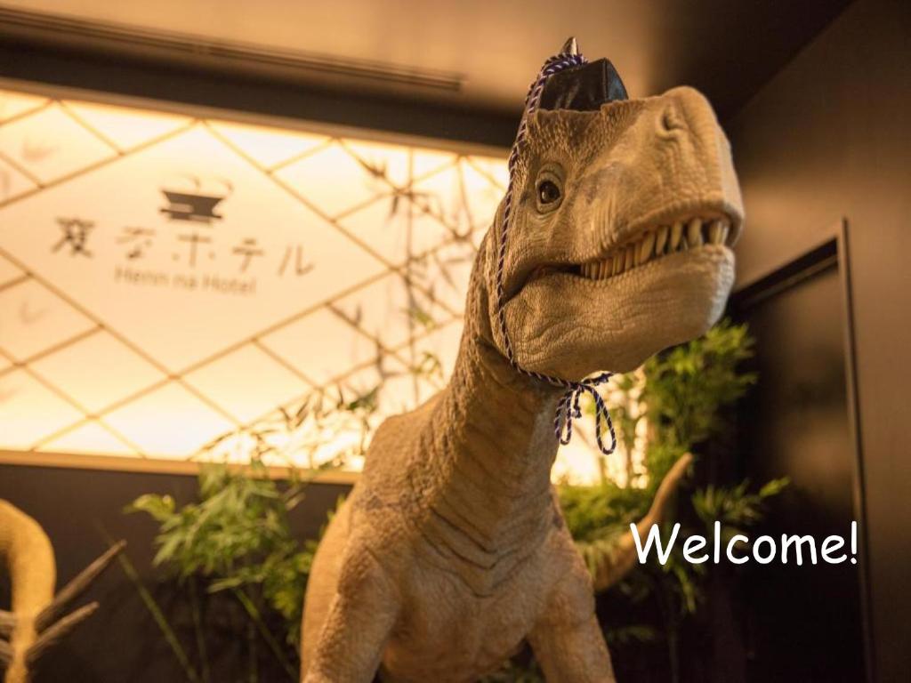 东京Henn na Hotel Tokyo Nishikasai 的恐龙玩具站在一个欢迎的标志旁