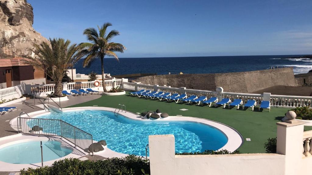 La EstrellaVivienda con encanto, en un complejo con piscina的一个带椅子的游泳池,背景是大海