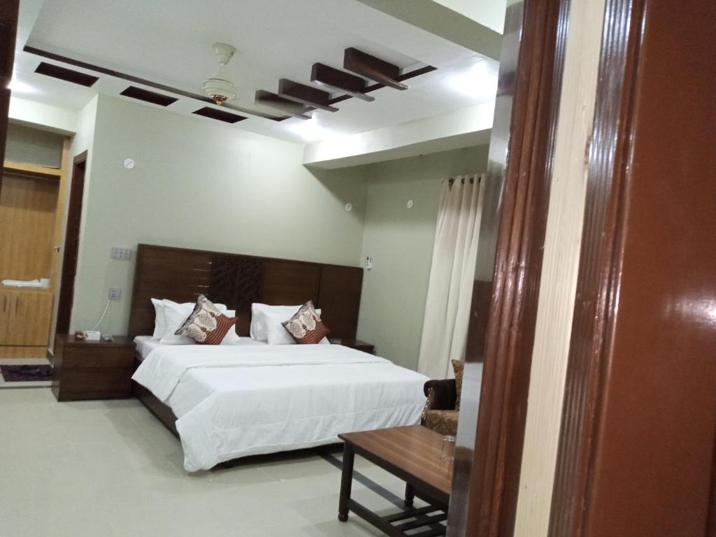 伊斯兰堡Hotel AL MARKAZ的卧室配有一张白色的大床和一张桌子