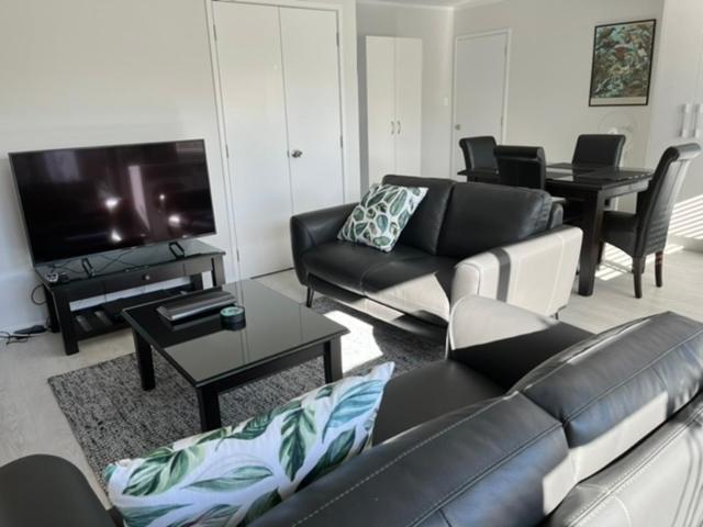 罗托鲁瓦Rotorua Central Hosted B&B的客厅配有黑色真皮沙发和电视