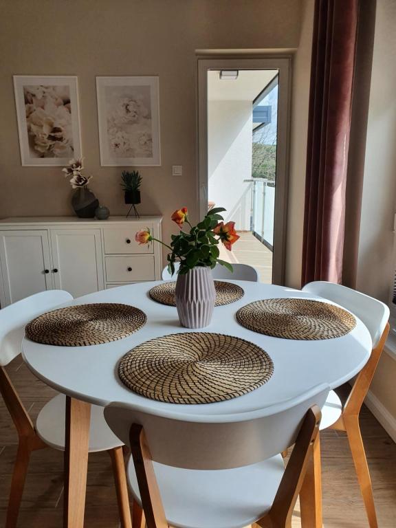 斯武普斯克Zamiejska Modern Apartments的一张带椅子的白色桌子和一个花瓶