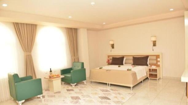 MidyatAkitu Hotel的一间卧室配有一张床和两张绿色椅子