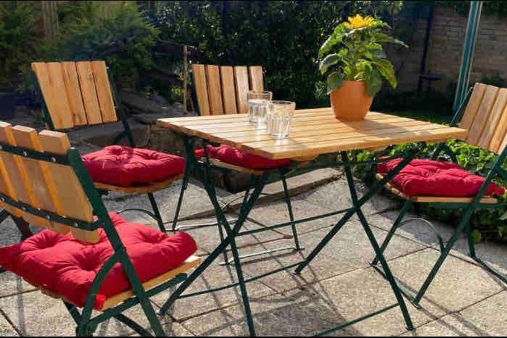 瓦伦Ferienwohnung Lavendel的庭院里配有一张木桌和椅子及红色靠垫