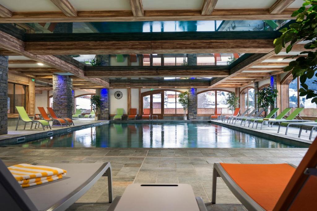 沙泰勒昂日尔小屋CGH公寓式酒店的大楼内一个带桌椅的游泳池