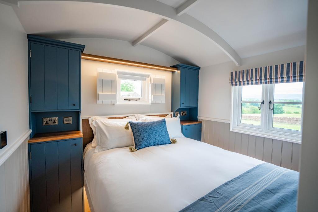 彭里斯Inglewood Shepherd's Huts的一间卧室配有一张带蓝色橱柜的床和窗户。