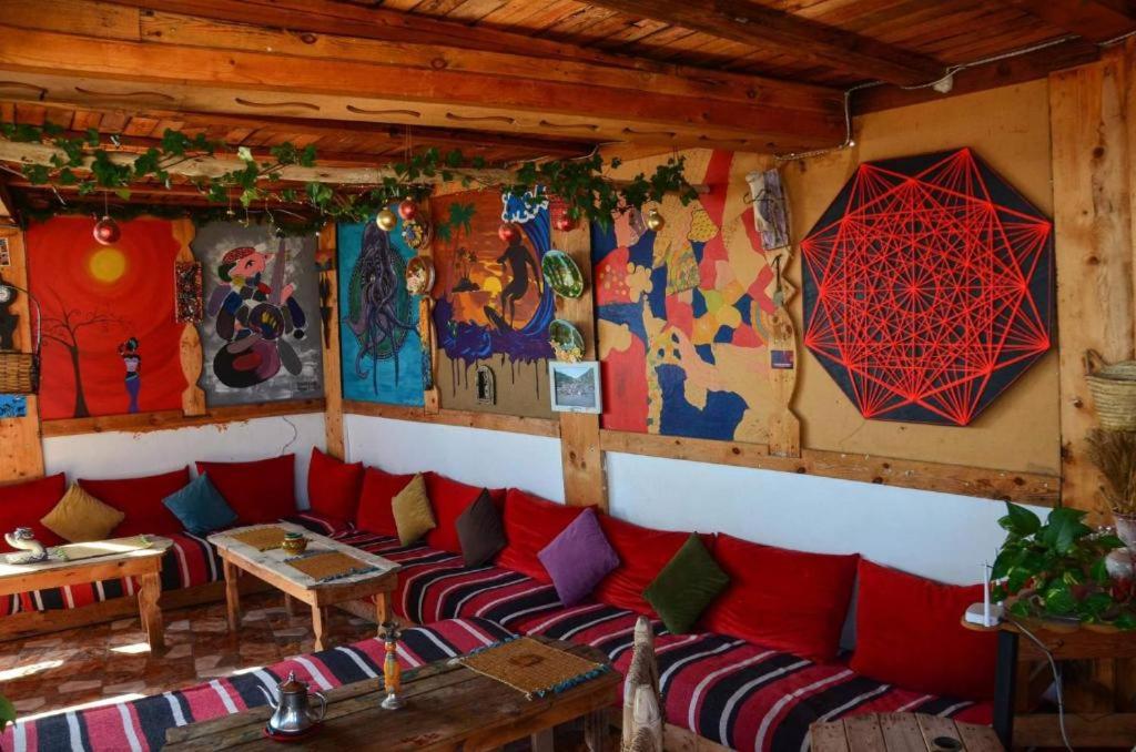 塔哈佐特Tayought Surf House的一间设有红色沙发的客房,墙上挂有绘画作品