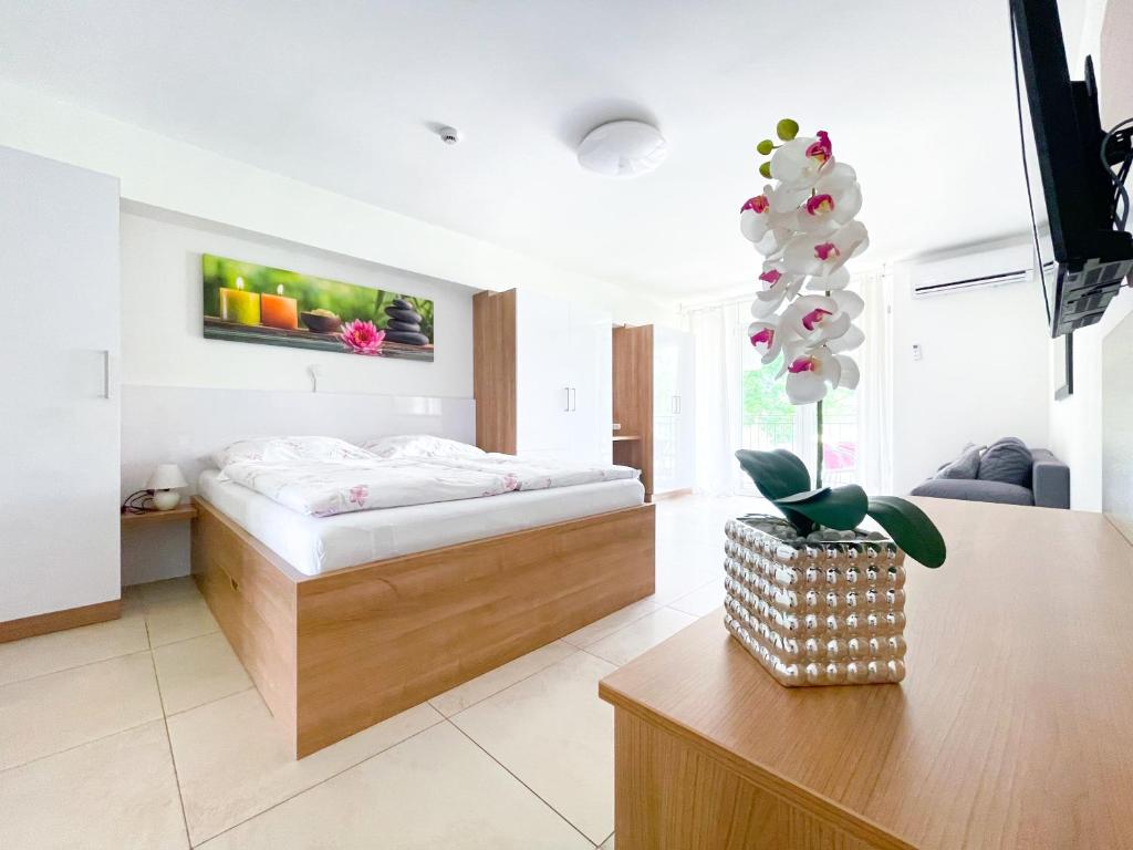 塞格德Tisza Gyöngye Apartmanok的一间卧室配有一张床和一张植物桌子