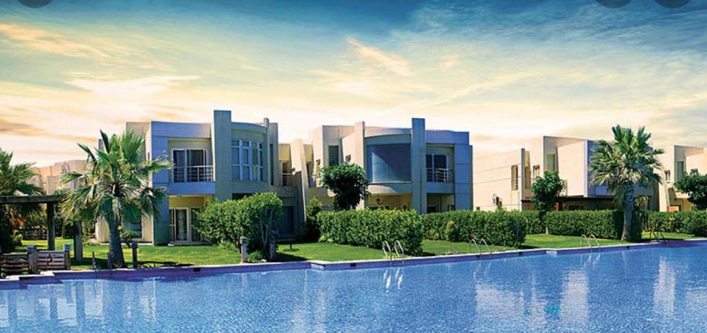 亚历山大North coast sedra resort villa قريه سيدرا الساحل الشمالي的一座别墅,在一座建筑前设有一个游泳池