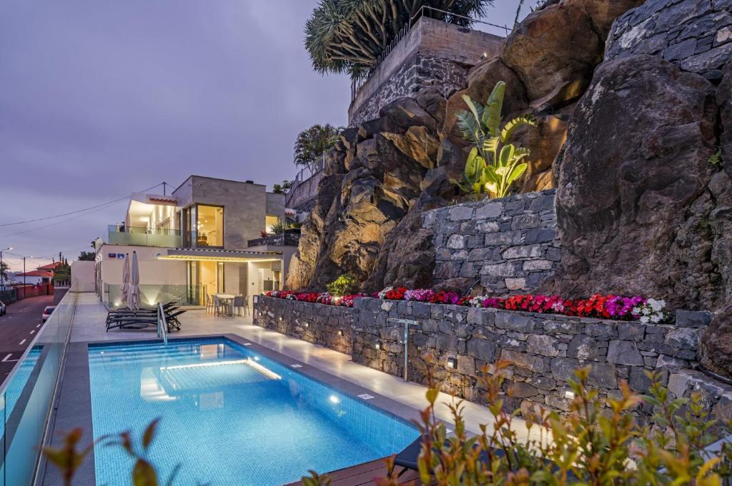 丰沙尔Villa Grandview by Villa Plus的岩石墙前的游泳池