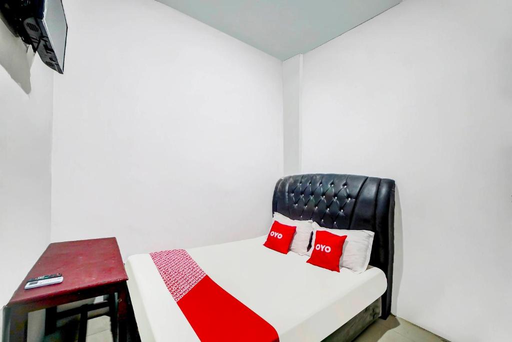 棉兰OYO 91224 Brayan Guest House的配有红色枕头和凳子的床的客房