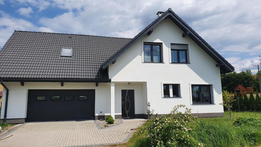 库多瓦-兹德鲁伊Dom Zakątek, Kudowa Zdrój的一间白色的房子,有黑色的屋顶和一个车库