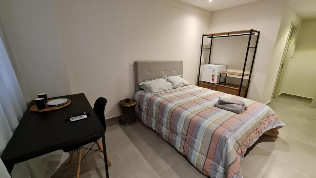 坎普斯戈伊塔卡济斯Flat Hotel América Campos Pelinca 301的一间卧室配有一张带桌子和镜子的床